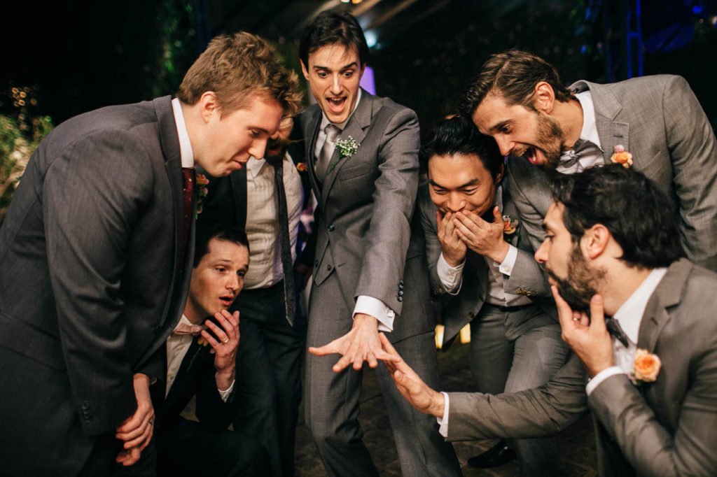 Noivo e padrinhos olhando a aliança do noivo